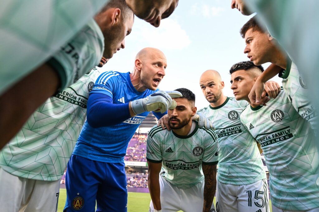 brad guzan leading a team talk in a huddle for atlanta united